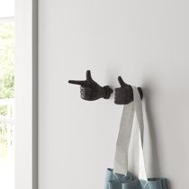 a pair of gloves hanging on the side of a wall with two fingers pointing at something