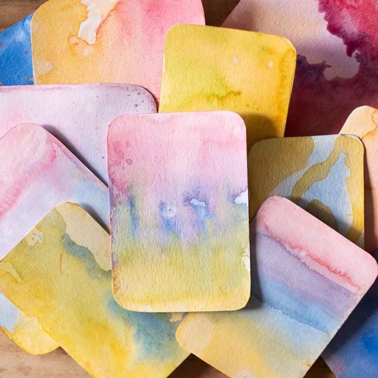 watercolor paper coasters sitting on top of each other in front of a wooden table