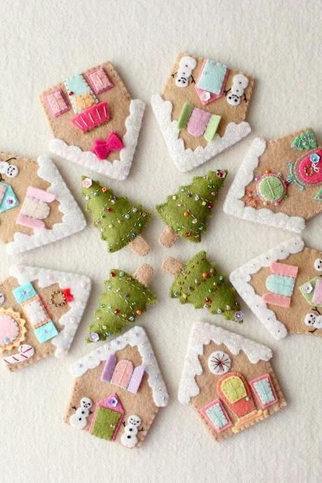 decorated cookies arranged in the shape of small houses and trees on a white surface with snow flakes