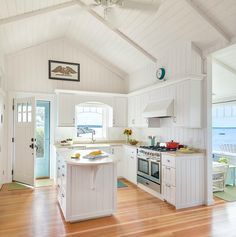 an open concept kitchen with white cabinets and wood flooring, along with large windows overlooking the ocean