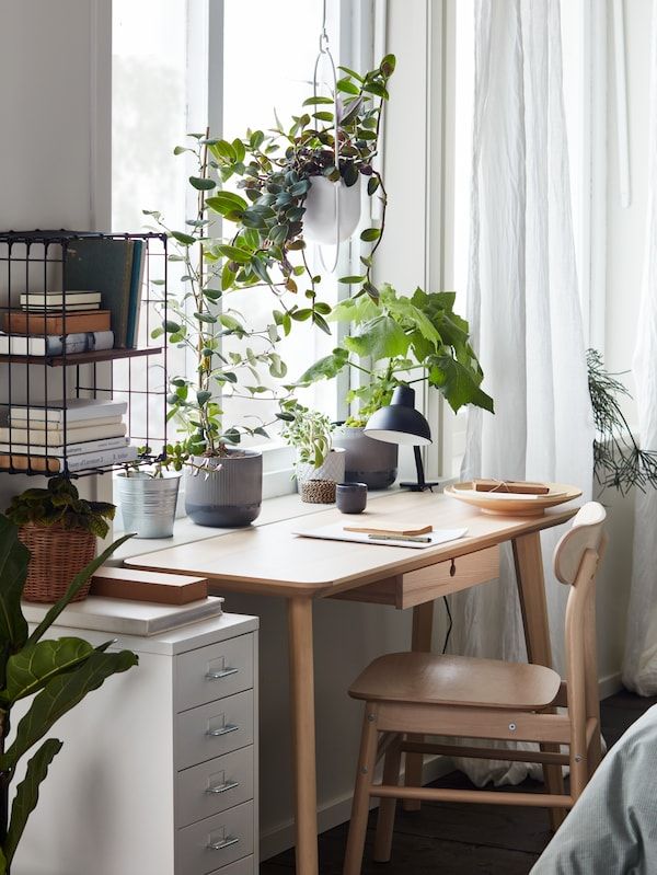 a table with some plants on top of it next to a window and a chair