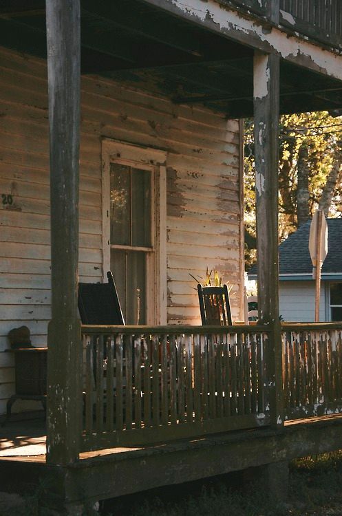 an old wooden porch with chairs on it