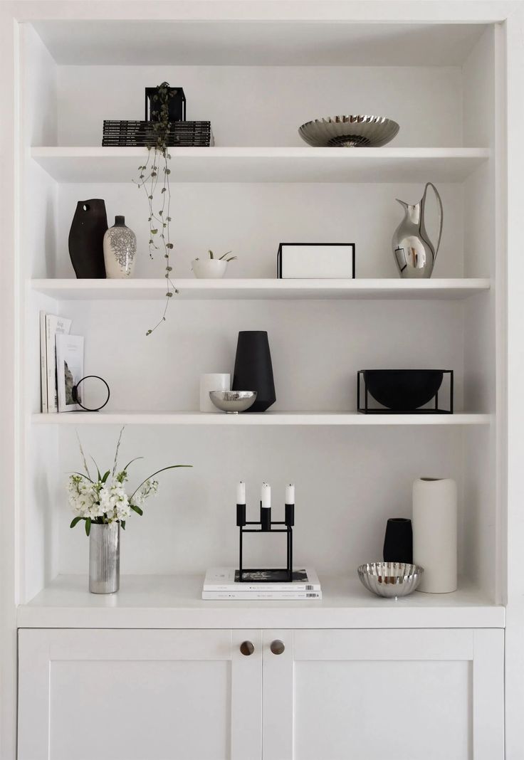 a white bookcase filled with books and vases