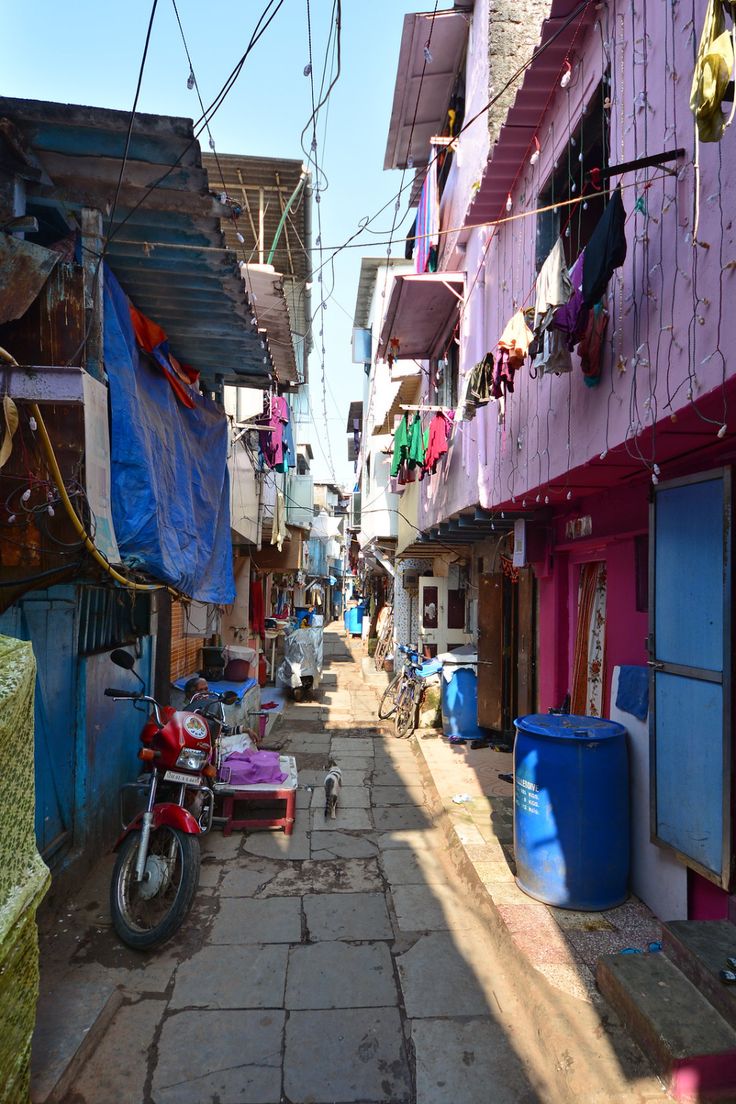 an alley way with laundry hanging on the clothes line and a motorcycle parked in front of it