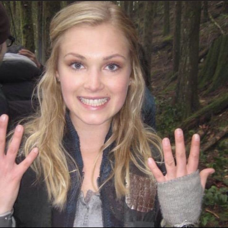 a woman with her hands up in front of her face and smiling at the camera