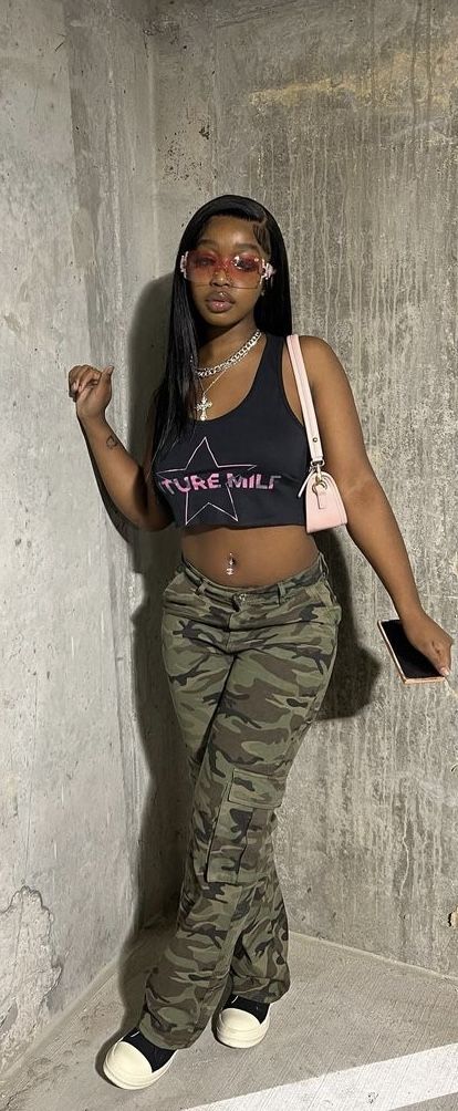 a woman in camo pants and tank top posing for the camera with her hand on her hip