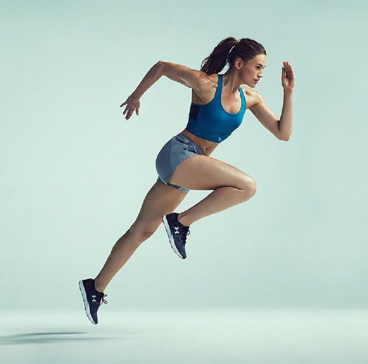 a woman is running in the air with her leg up and one hand on her hip