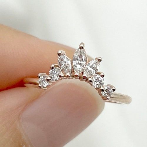 a woman's hand holding a ring with three pear shaped diamonds on top of it