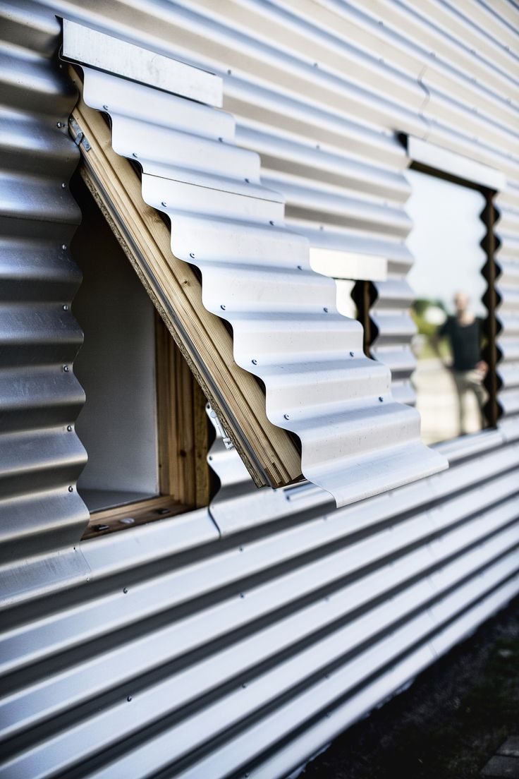 an open window on the side of a building with metal slats covering it's windows