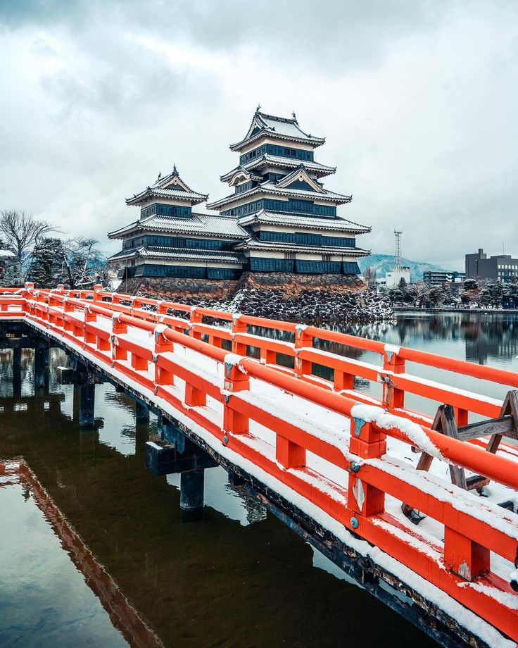 an orange and white bridge over water with buildings in the background