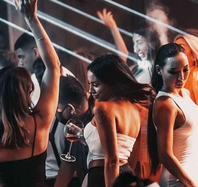 two women dancing in front of a group of other people at a club or bar