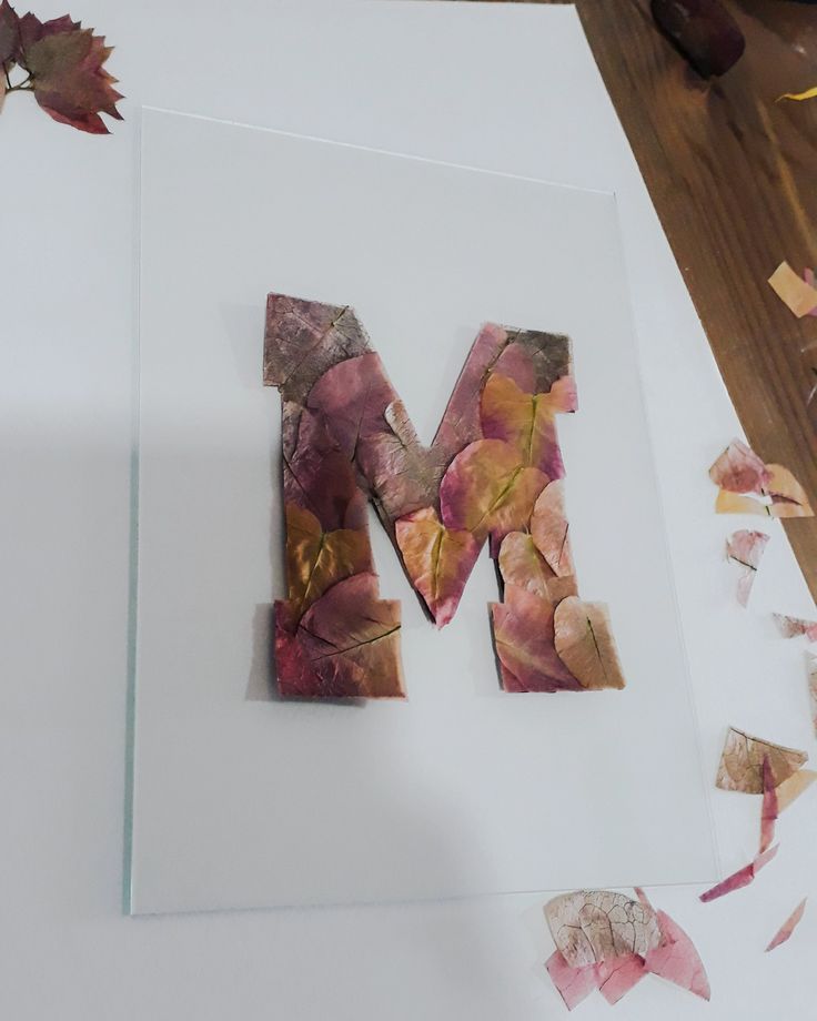 the letter m is made up of leaves and other things that are scattered around it