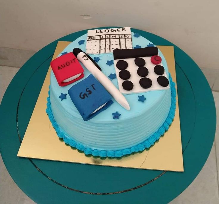 a birthday cake decorated with blue frosting and various items including a notebook, calculator, pen and calendar