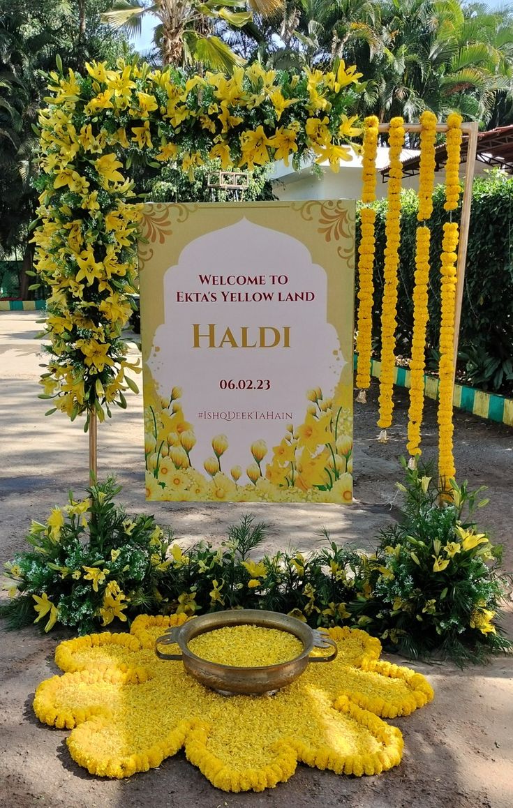 the welcome sign to haldi is surrounded by yellow flowers and greenery in front of it