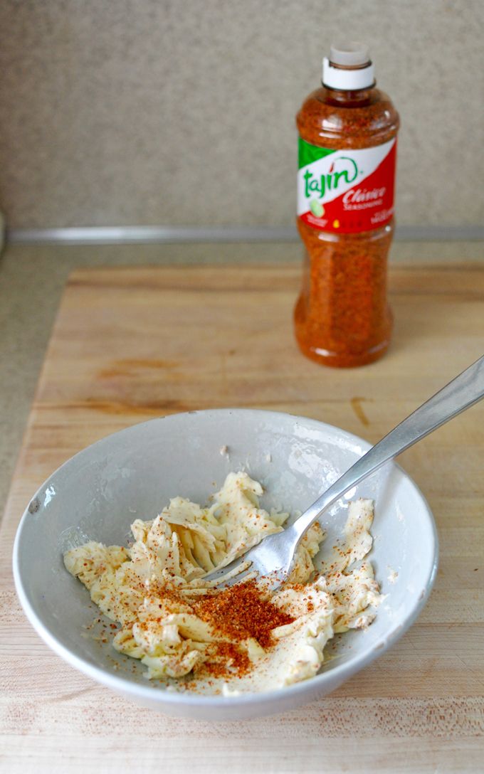 a white bowl filled with food on top of a wooden cutting board next to a bottle of seasoning