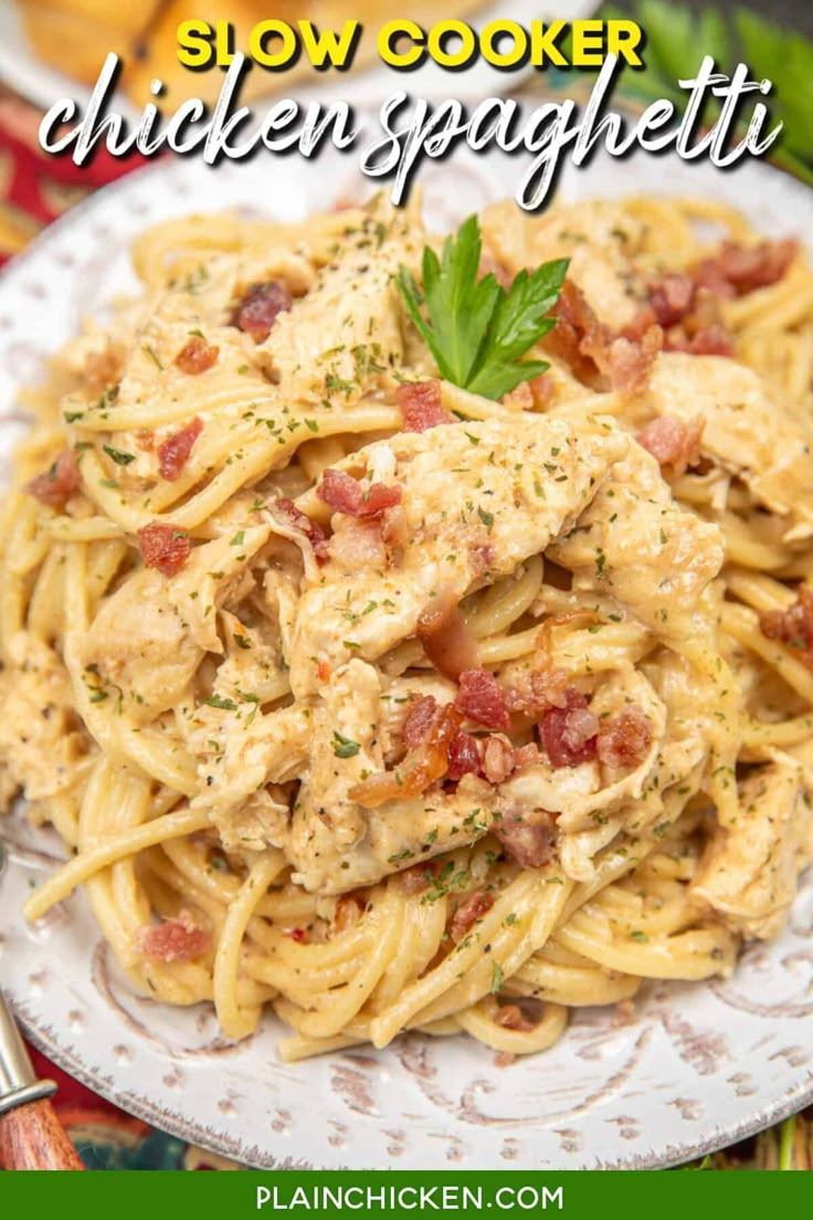 a white plate topped with pasta covered in chicken and sauce on top of a wooden table