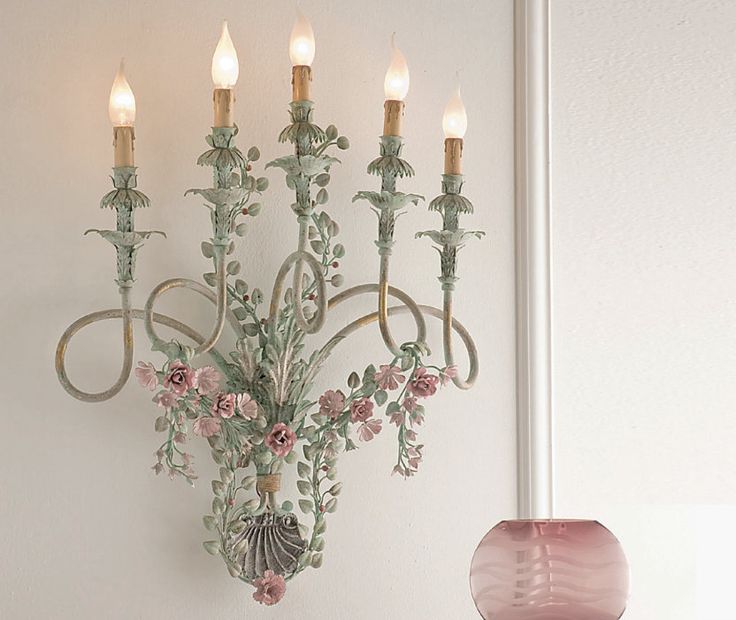 a chandelier hanging from the side of a wall next to a vase with flowers on it