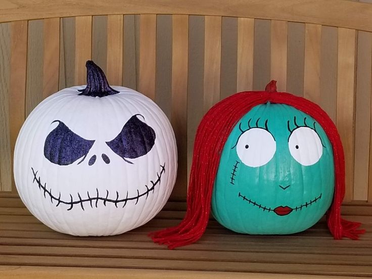 two pumpkins with faces painted on them sitting on a bench