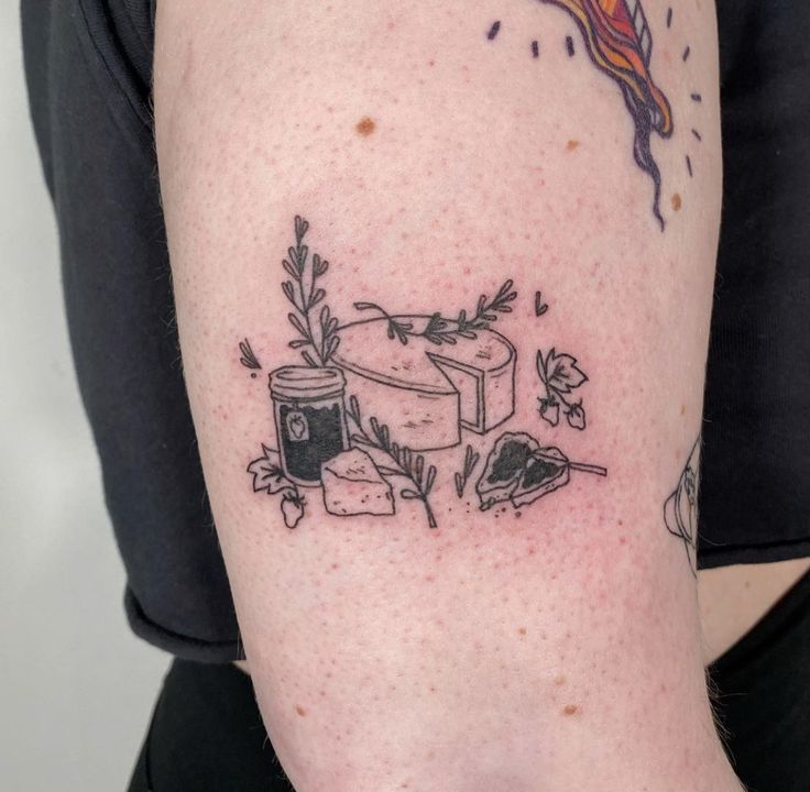 a woman's arm with tattoos on it and an image of a cake in the middle