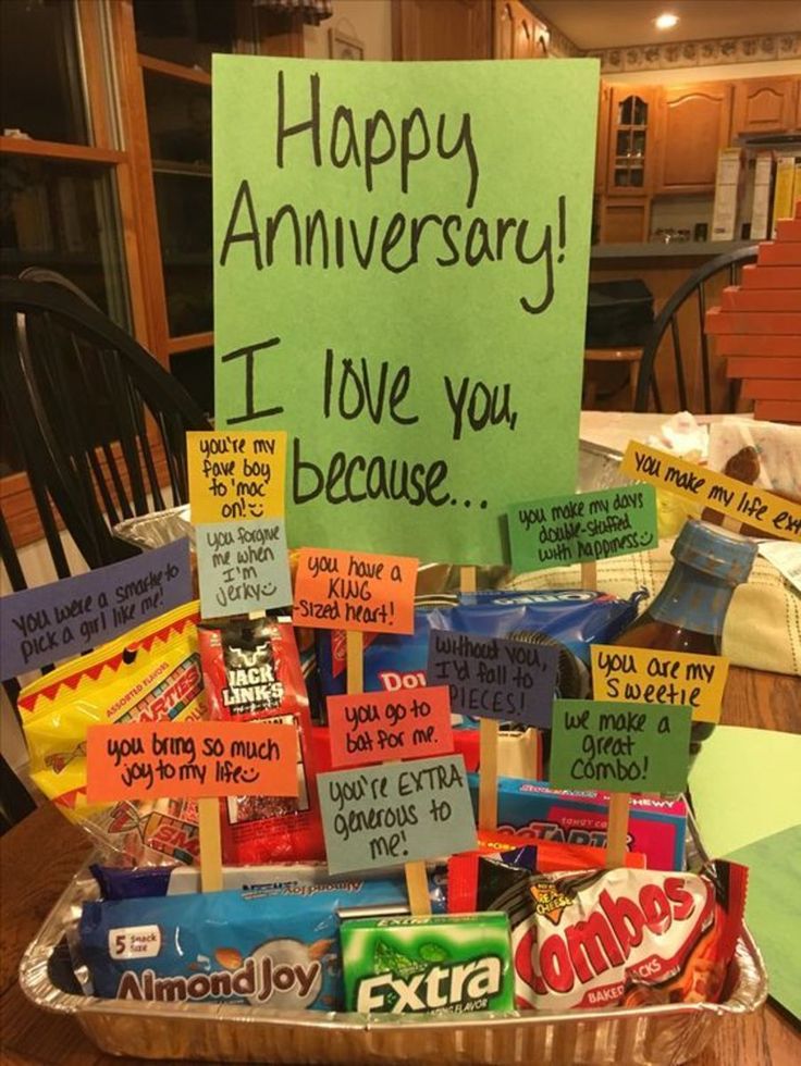 a basket filled with lots of candy sitting on top of a table next to a sign that reads happy anniversary i love you because