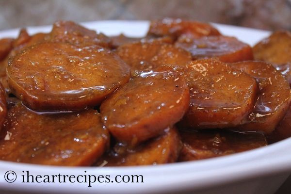 a white bowl filled with cooked carrots covered in brown sauce