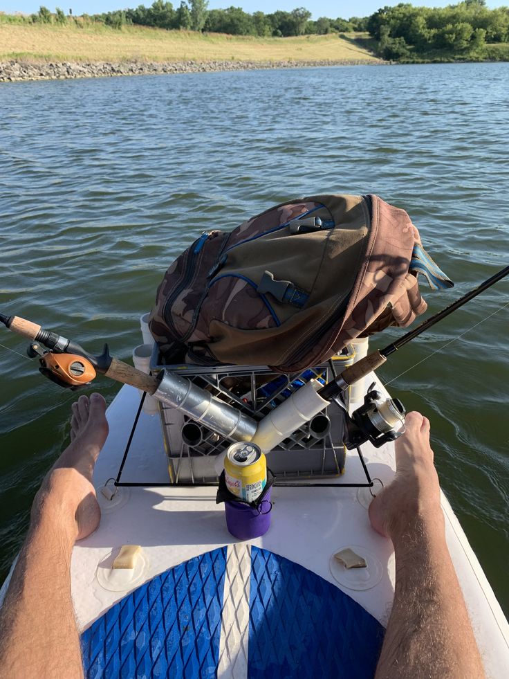 a man is sitting in a boat with his feet on the water and fishing rods