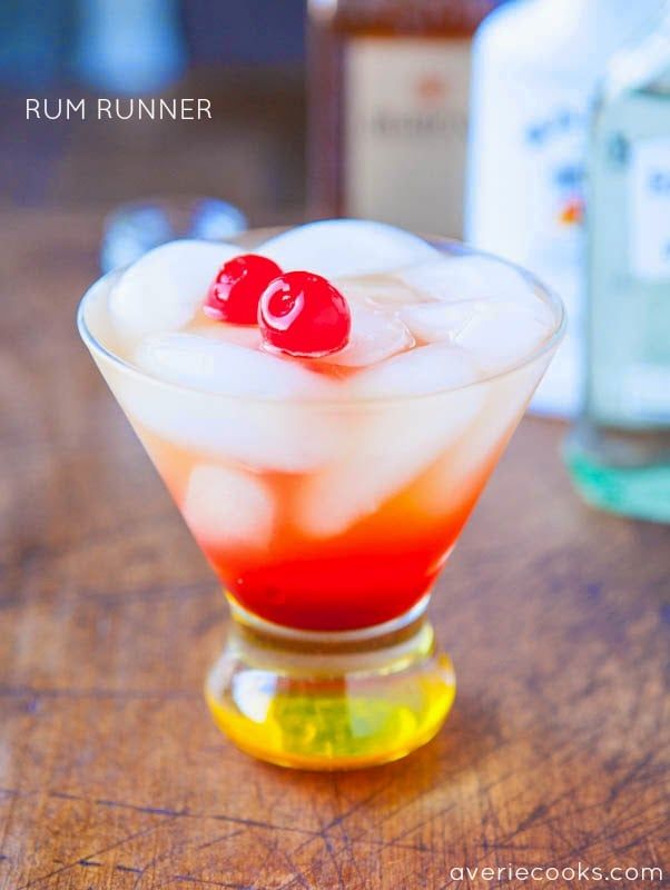 a drink with ice and cherries sitting on a table