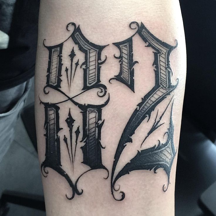 a close up of a tattoo on the leg of a person's arm with letters and arrows