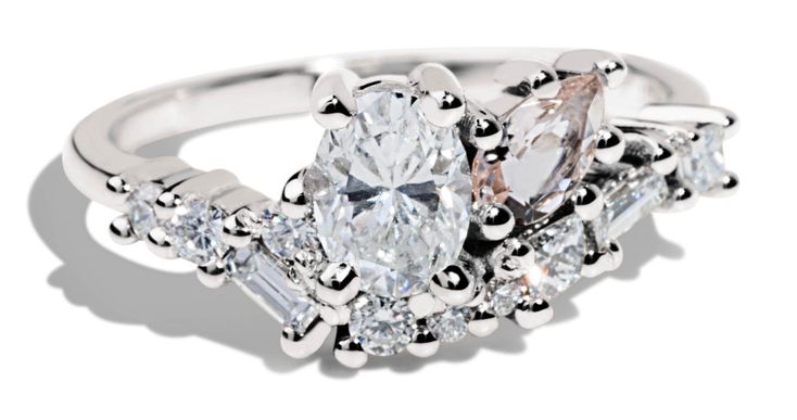 a three stone ring with diamonds on the sides and an oval shaped diamond in the center