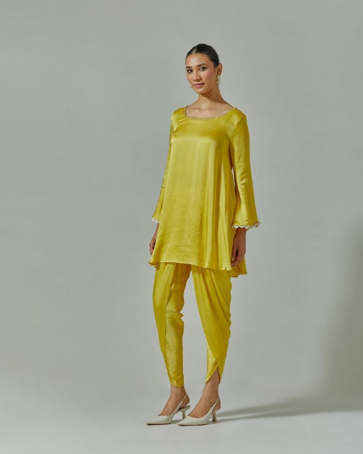 Our Misted Yellow suit set is presented in a soothing shade of yellow. This festive garment was handcrafted from soft modal satin. Delicate cutdana, beaded and zari work at the yoke and cuffs enhance its appeal. It is paired with a tonal embroidered net dupatta to enhance its appeal. For a more dramatic look, choose a pair of dhoti pants to go with the set Color : Yellow Fabric : Modal satin and meshCare : Dry clean onlyFit : Flared The model wears size S. Elegant Yellow Palazzo Set With Straight Kurta, Elegant Yellow Kurta For Navratri, Traditional Drape Pant Set With Gota Work For Eid, Eid Pant Set With Gota Work And Traditional Drape, Eid Traditional Drape Pant Set With Gota Work, Eid Gota Work Pant Set With Traditional Drape, Elegant Navratri Pant Set With Gota Work, Yellow Silk Long Sleeve Traditional Wear, Elegant Yellow Silk Sharara