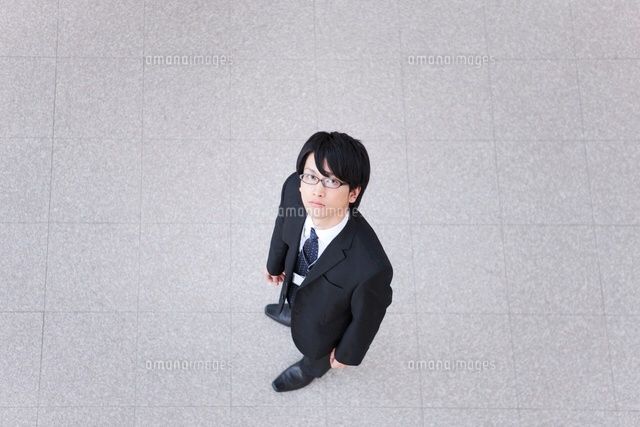 an overhead view of a man in a suit and tie sitting on the ground looking down