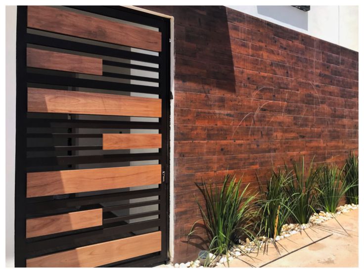 a wooden door is open on a brick wall next to some grass and plants in front of it