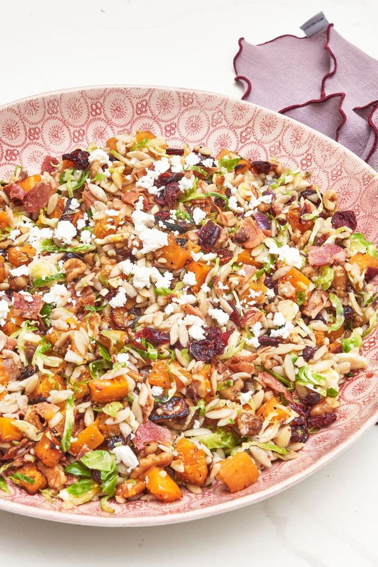 a large bowl filled with lots of food on top of a table next to utensils