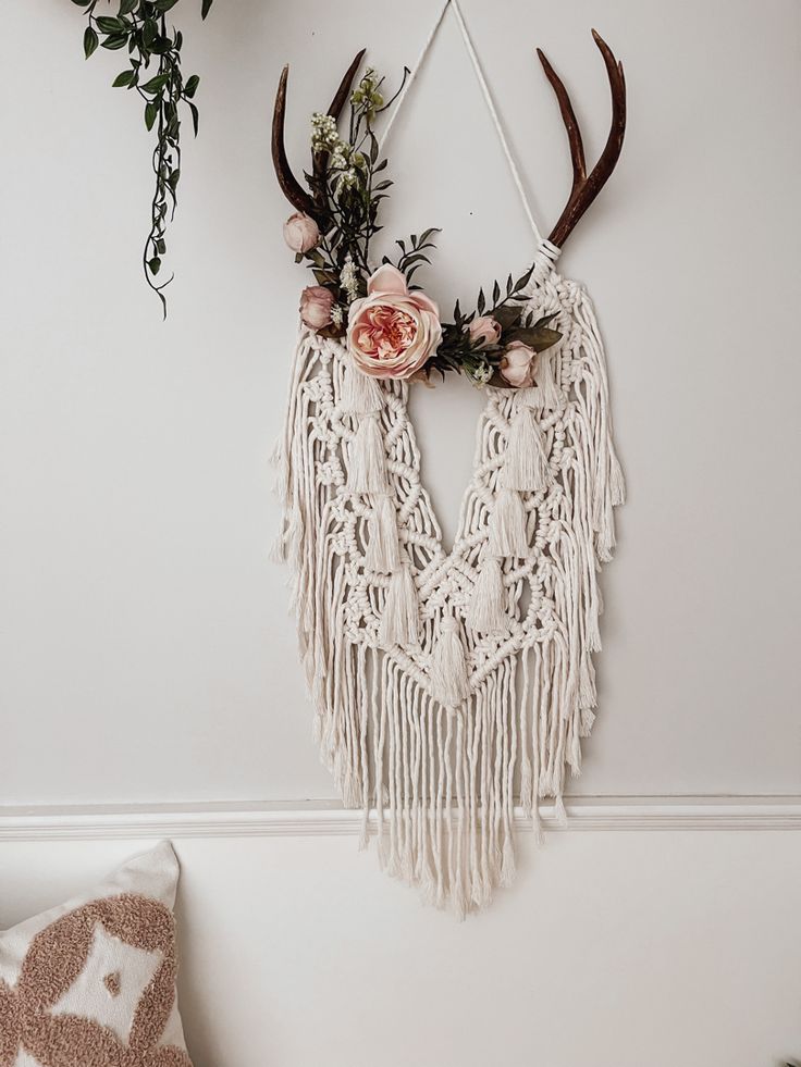 Florals adorn an intricate macrame wall hanging on a set of deer antlers. Made with 100% cotton cord Boho Theme Bedroom Decor, Boho Deer Antlers Decor, Crafts With Antlers Diy, Macrame Antler Diy, Hanging Antlers On Wall, Deer Horn Macrame, Boho Antler Decor, Macrame With Deer Antlers, Macrame With Antlers