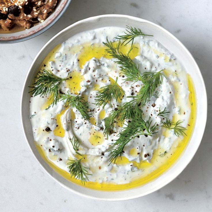 a white bowl filled with dip and topped with dill