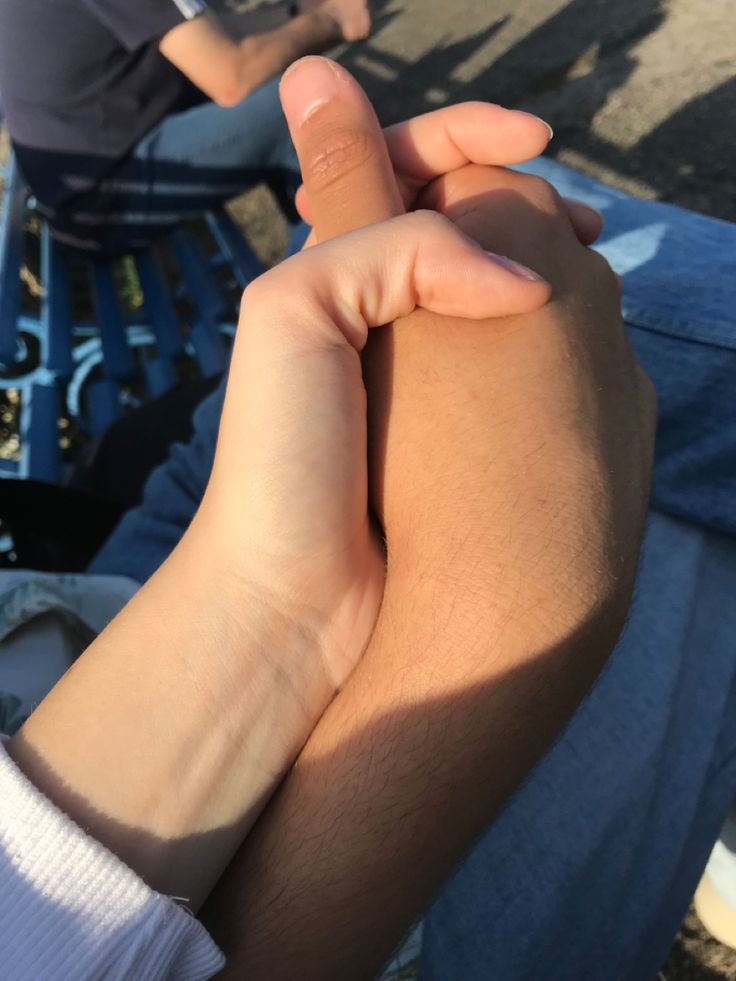 two people sitting on a park bench holding hands with one person's arm in the air