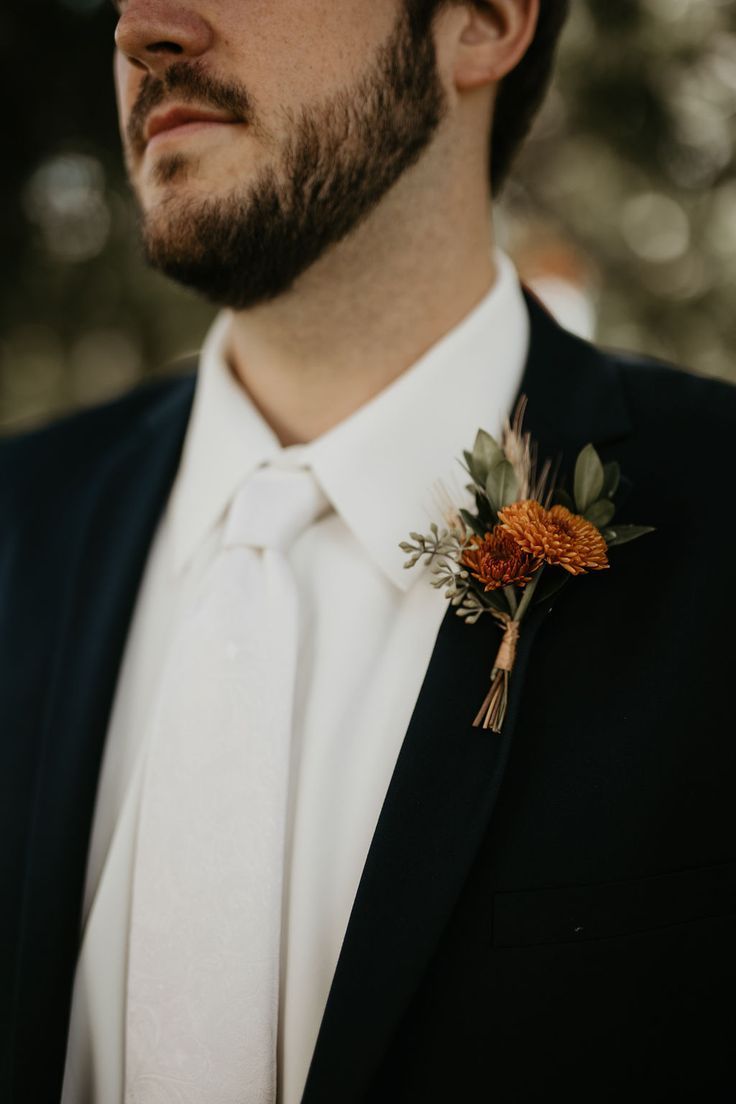 a man in a suit and tie with an orange boutonniere on his lapel