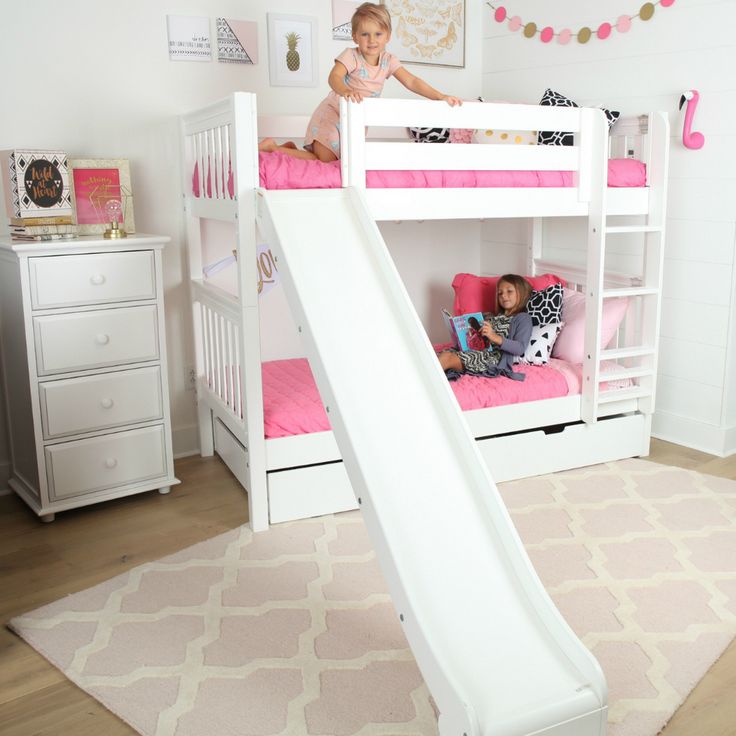 a white bunk bed with a slide in the middle and two children laying on it