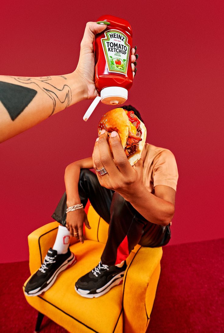 a man sitting on a yellow chair holding a bottle of ketchup