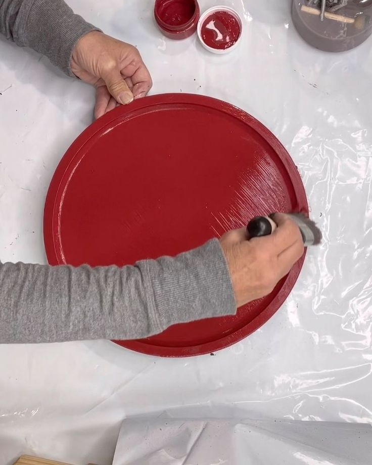 a person is holding a red plate on a table