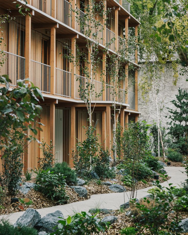 an apartment building with wooden balconies and landscaping