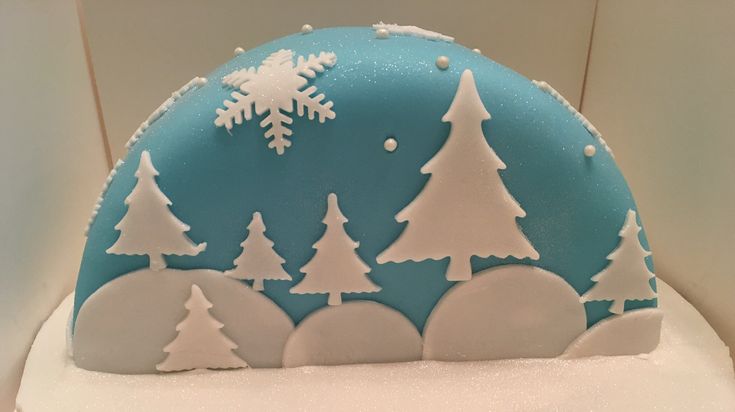 there is a blue and white cake with snow on it that looks like christmas trees