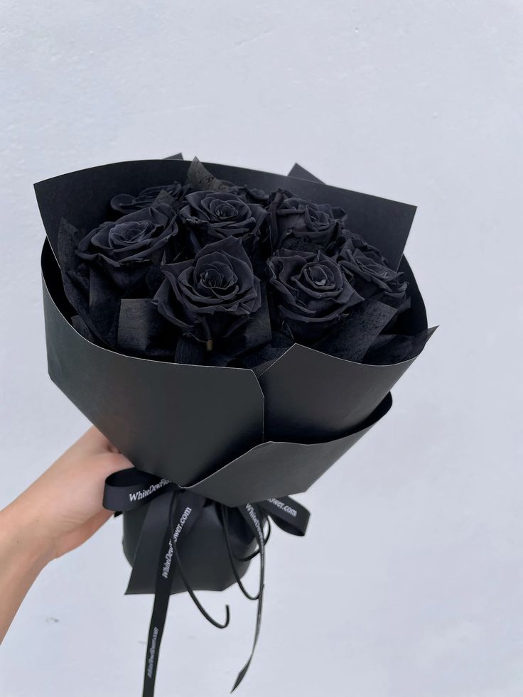 a hand holding a bouquet of black roses