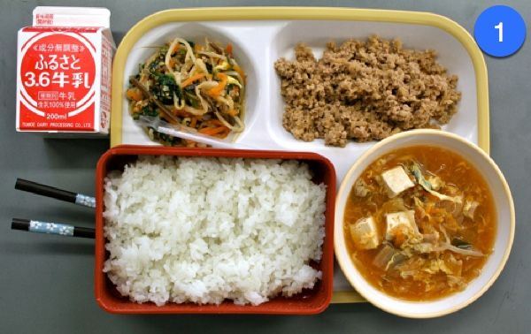 a tray with rice, meat and vegetables on it next to a container of soup