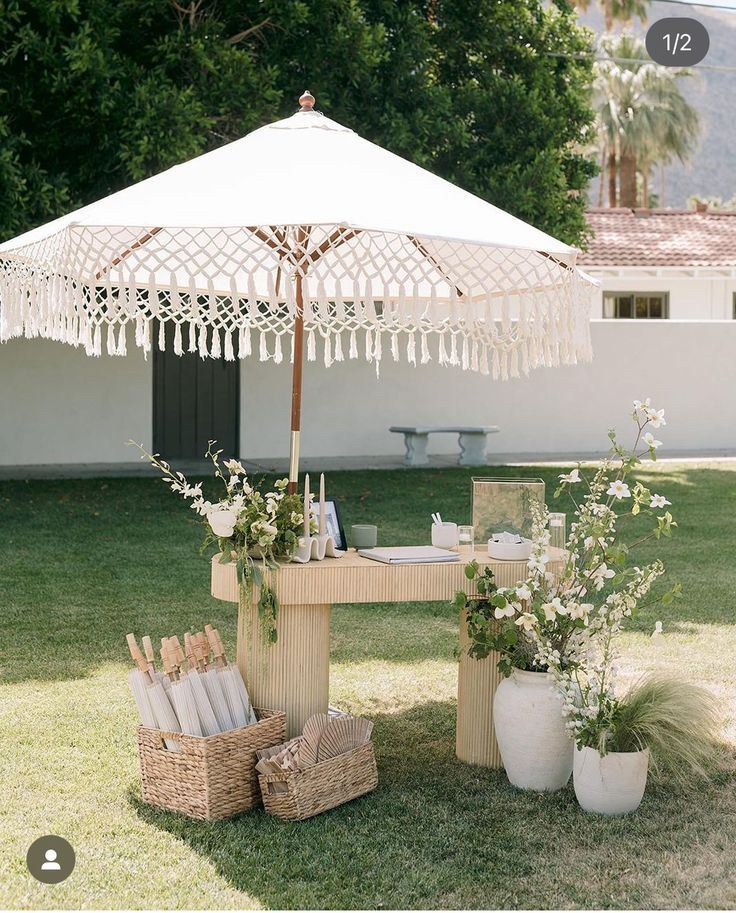 an umbrella is set up in the grass near some flowers and other items for sale