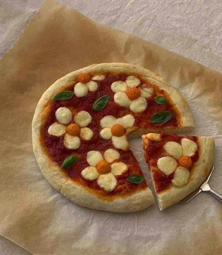 a small pizza on a piece of parchment paper with one slice cut out and the other half eaten