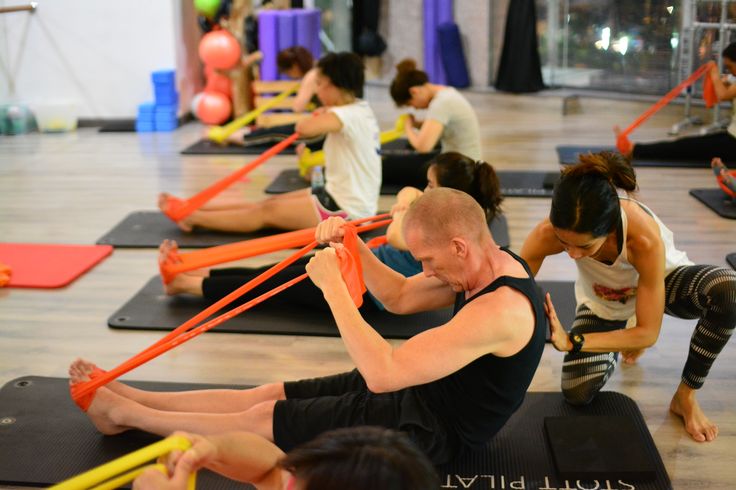 a group of people doing stretching exercises on exercise mats in a gym with resistance bands