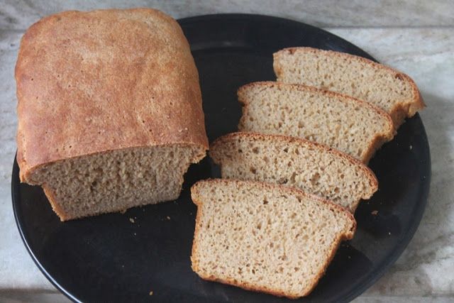 sliced loaf of bread sitting on top of a black plate next to slices of bread