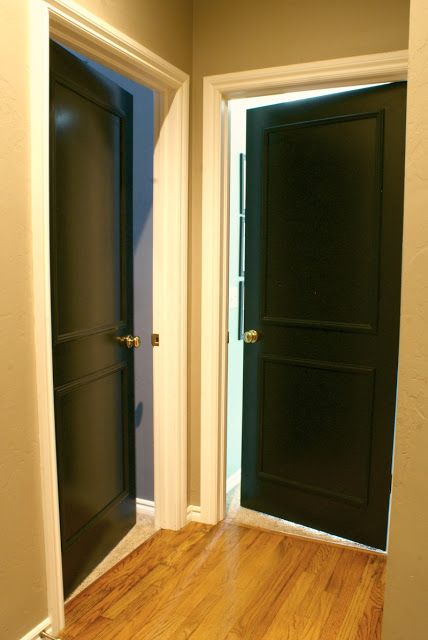 an empty room with two black doors and wood flooring on either side of the door