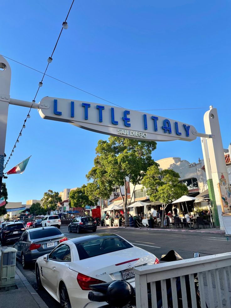 a white car parked under a sign that says little italy